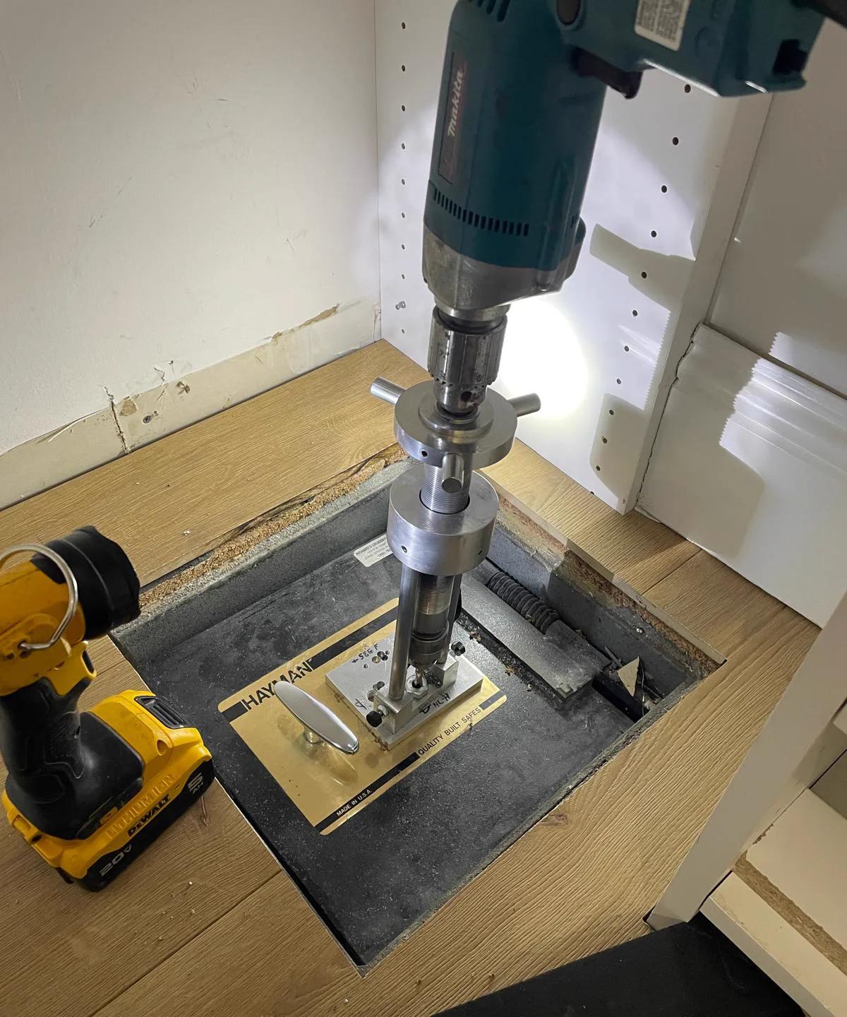 Locksmith drilling a small precise opening hole in a floor safe